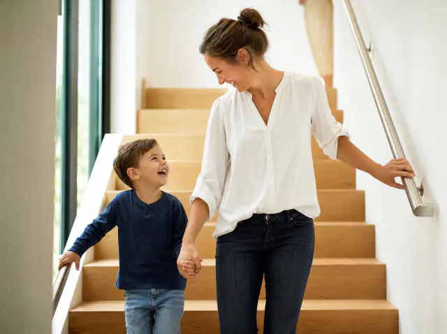 Handläufe Innenbereich – Mutter und Kind sicher auf der Treppe Mutter und Sohn gehen Hand in Hand die Treppe mit Innenhandlauf hinunter