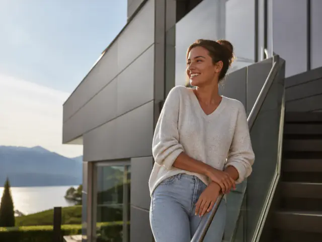 Lächelnde Frau geniesst den Ausblick an einem Handlauf für Aussentreppen